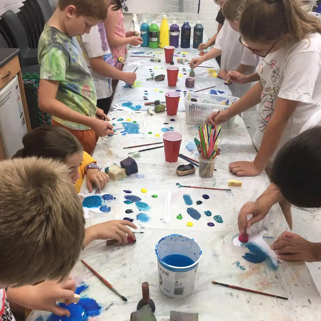 Children painting on table with paint.